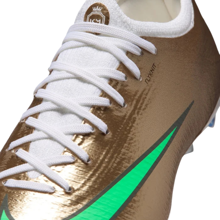 Nike Jr Vapor 17 Pro FG Mbappe kids' soccer cleats in metallic gold and green glow with Nike branding and studded outsole.